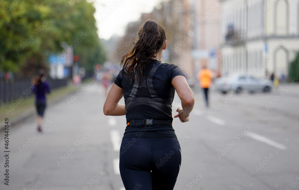 Brunette woman running on empty city road, blurred crowd running ahead of her. Athletes taking part in sports event Brunette woman running on empty city road, blurred crowd running ahead of her. Athletes taking part in sports event