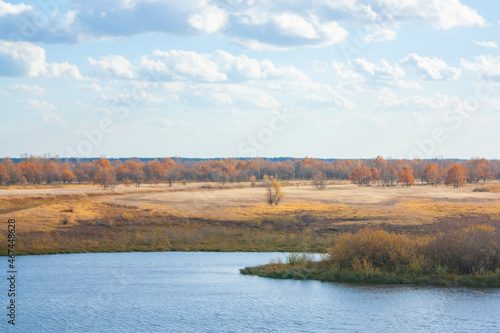 Autumn landscape on a bright sunny day. Yellow vegetation on the bank of the blue river.