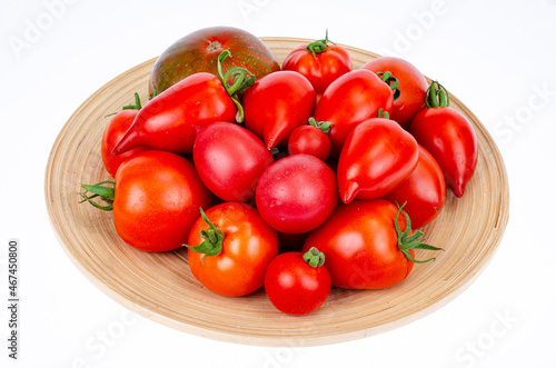 Assorted homemade colorful tomatoes different shapes on wooden plate. Studio Photo.