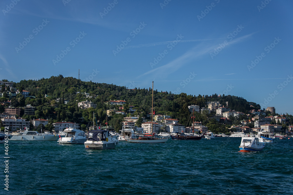 A beautiful Bosphorus shore view on a sunny day with lot of boats on the shore and houses over the green hills and a part of historic Rumeli castle in the back. A beautiful Bosphorus shore view on a sunny day with lot of boats on the shore and houses over the green hills and a part of historic Rumeli castle in the back.