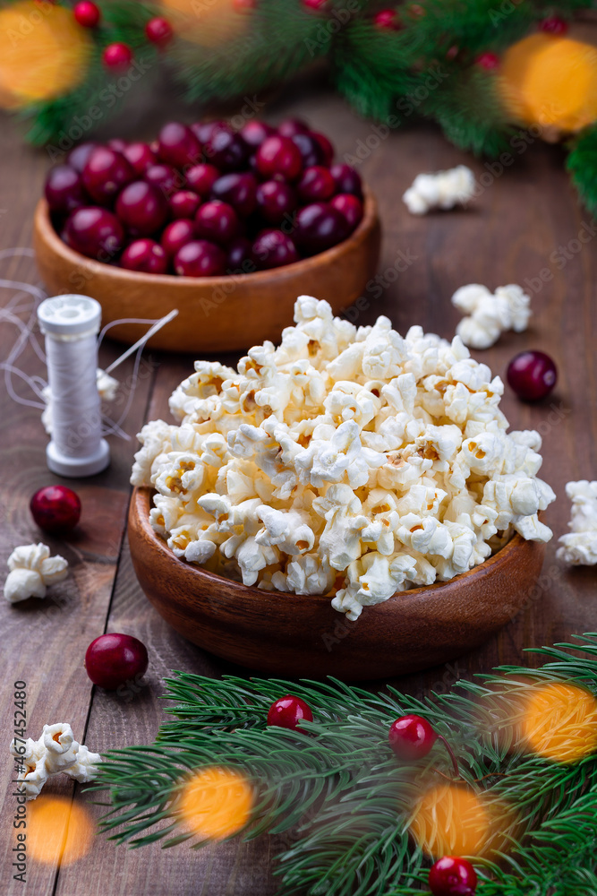 Ingredients for traditional handcrafted Christmas popcorn garland with red cranberries, bokeh effect