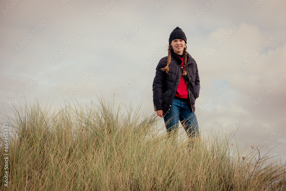A teenage girl on a hike through nature and the coastal countryside in cold weather clothing