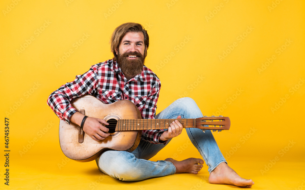 Obraz premium brutal bearded man wear checkered shirt having lush beard and moustache playing the guitar, music