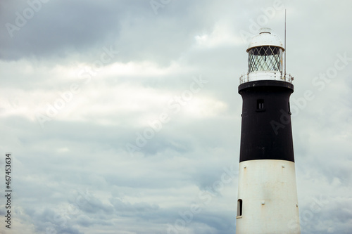 Close up of a cylindrical brick tower lighthouse with black and white bands with white space