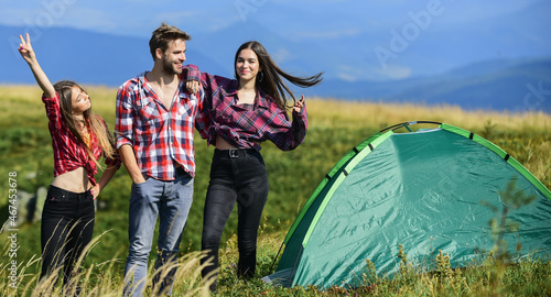 Summer relax. mountain tourism camp. hiking outdoor adventure. group of people spend free time together. man and two girls pitch tent. wanderlust discovery. friends camping. reach destination place photo