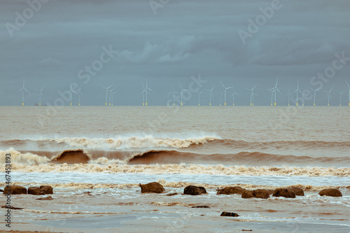Coastal landscape at Spurn point, showing turbulent sea waves and the wind farm on a stormy day photo