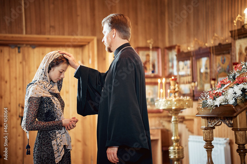 a priest blesses a teenage girl in a headscarf in an Orthodox church after a festive church mass