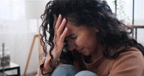 Sad woman crying sitting on sofa at home