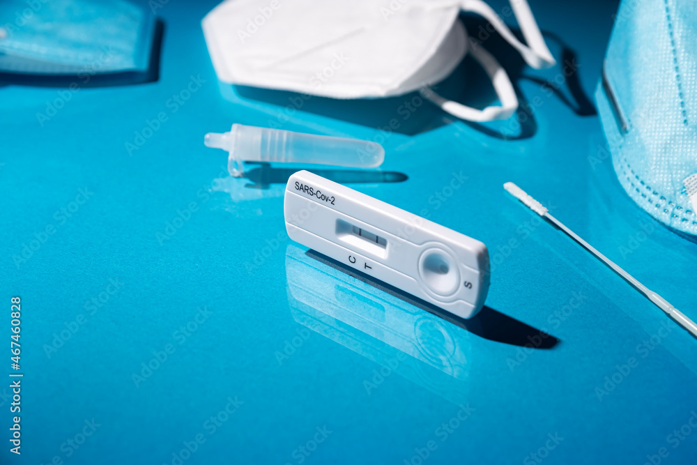 Close up image of Rapid test kit device for Covid-19 showing positive result. Lab card kit test for coronavirus SARS-CoV-2 virus. Fast test COVID-19 on blue surface Close up image of Rapid test kit device for Covid-19 showing positive result. Lab card kit test for coronavirus SARS-CoV-2 virus. Fast test COVID-19 on blue surface