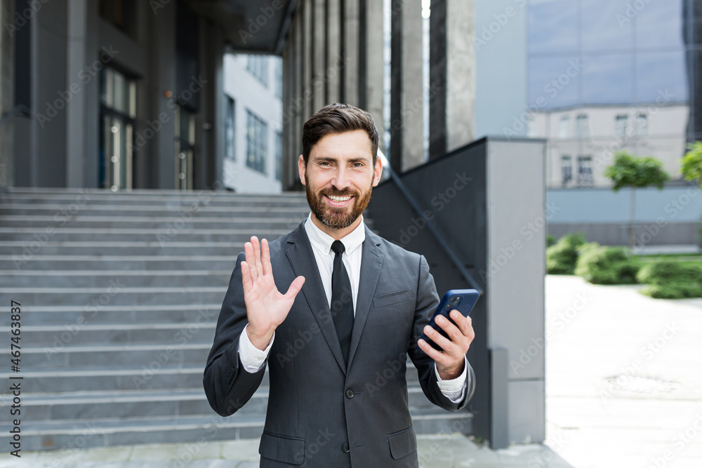 bearded businessman in a formal suit, talking on video call using smartphone on urban city street confident business man, entrepreneur or employee conversation a mobile phone background modern center bearded businessman in a formal suit, talking on video call using smartphone on urban city street confident business man, entrepreneur or employee conversation a mobile phone background modern center