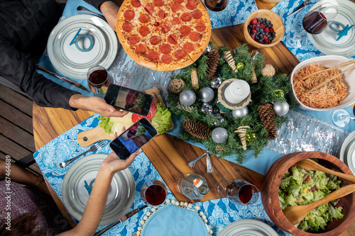 several hands with cellphones taking photos of food at the christmas dinner table