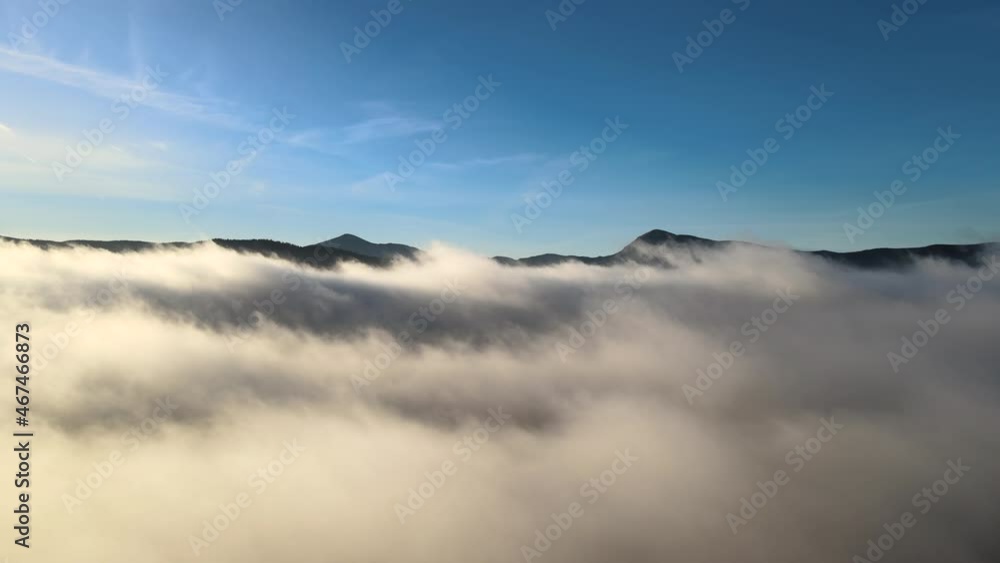 Aerial view of forward movement over white puffy clouds in wide mountain valley. Aerial view of forward movement over white puffy clouds in wide mountain valley.