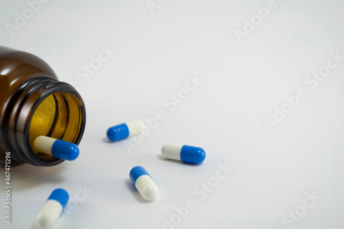 A glass bottle with medicines  blue and white pills lying near it. Prescription drugs and pills. photo