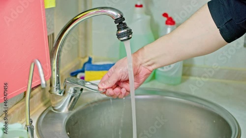 bare caucasian man washing striped dish with liquid soap detergent and blue-yellow sponge photo