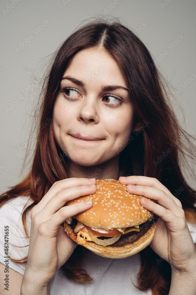 woman with a hamburger in her hands a snack fast food close-up woman with a hamburger in her hands a snack fast food close-up