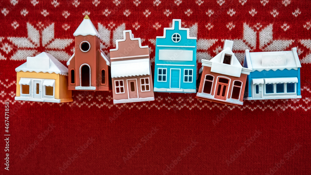 Christmas New Year real estate background. Toy typical european houses (Amsterdam/Netherlands, Brussels/Belgium, Copenhagen/Denmark) on red knitted background with Scandinavian ornament. Copy space.