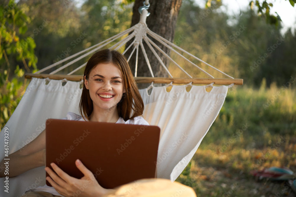 Naklejka premium woman with laptop and lies in a hammock vacation nature freelance