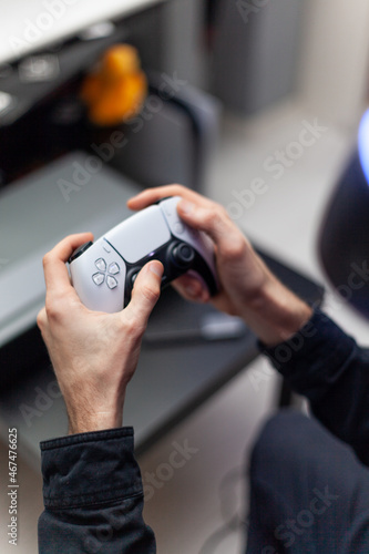 young man with beard in virtual reality helmet with gamepad joystick playing