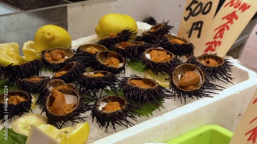 Slow motion of  famous golden egg urchin open and ready to eat on ice in Kyoto fish market. Fresh uni seafood from the Pacific ocean is a popular dish of Japan. Traditional Japanese food street.-Dan photo