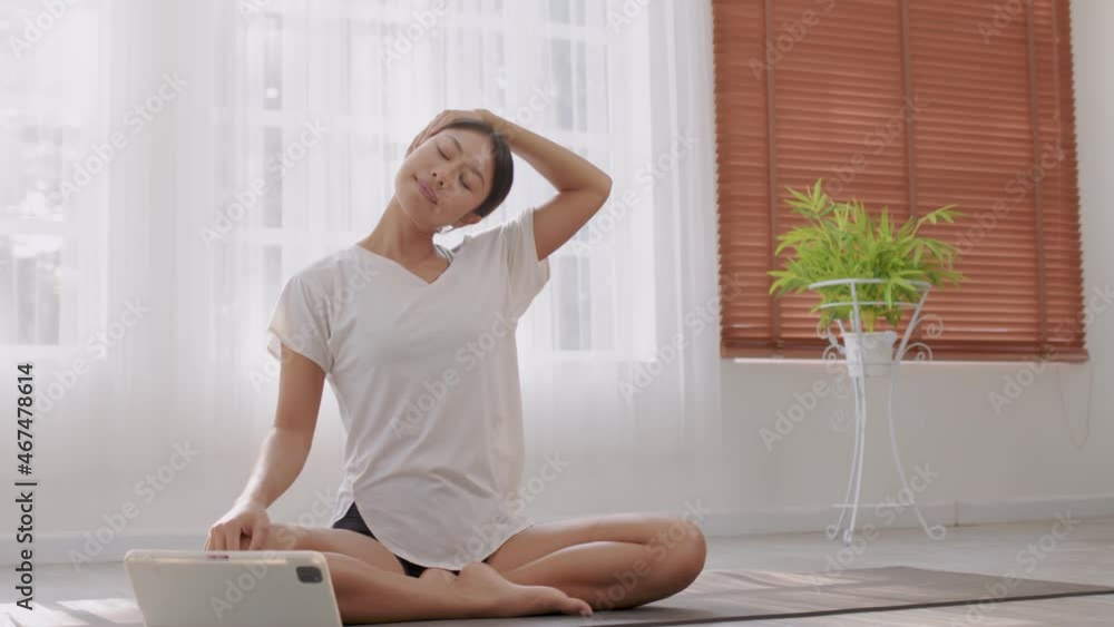 In the fitness studio, an Asian woman is studying online fitness training. Improve your health by extending your neck and meditating. In the fitness studio, an Asian woman is studying online fitness training. Improve your health by extending your neck and meditating.