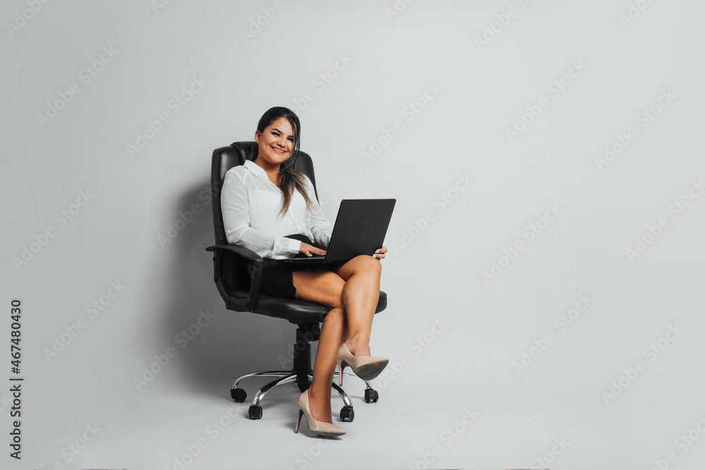 Full length of a business young woman latinx sitting executive chair holding computer technology concept. Full length of a business young woman latinx sitting executive chair holding computer technology concept.