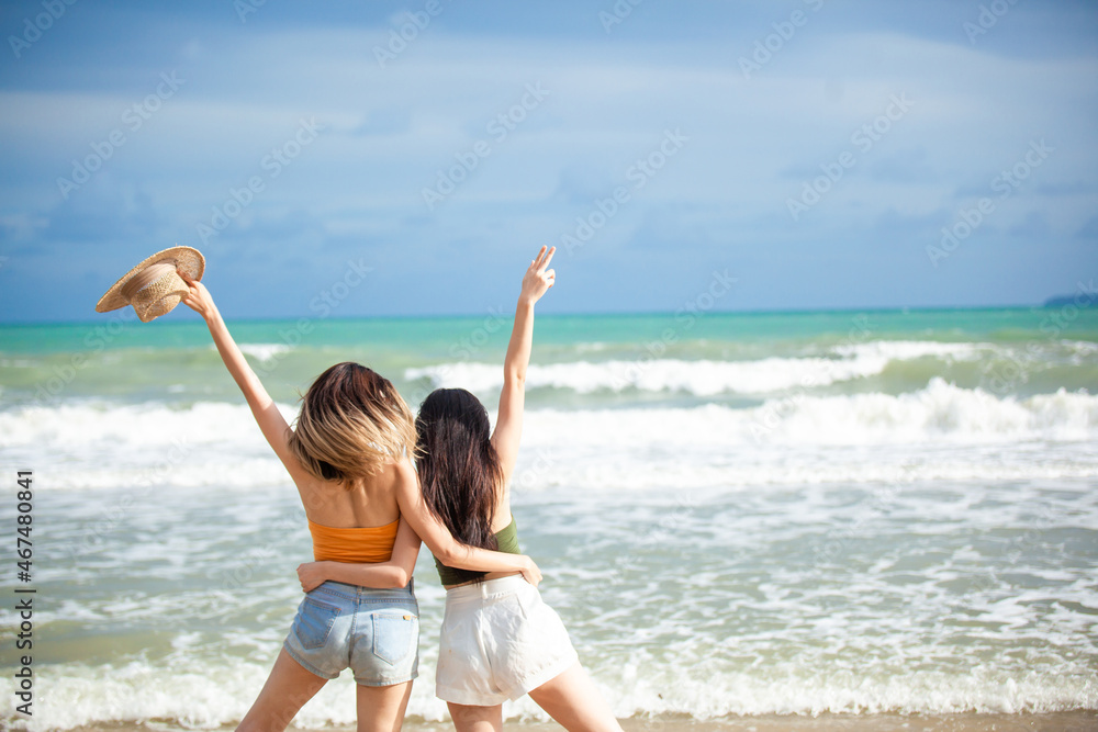 young women asian and friends enjoying on the beach. woman stand on sand of the sea and show hand in to sky.  Smile Freedom and happiness woman on beach
