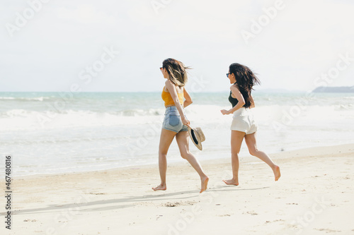 young women Asian and friends enjoying on the beach on a sunny day. Two young women Asian walking together on a beach. young women happy friends at sunset beach party runs to water
