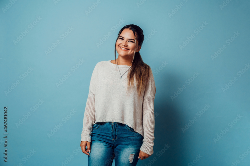 portrait of cheerful young woman latinx with casual clothes smiling looking at camera stand over blue background. portrait of cheerful young woman latinx with casual clothes smiling looking at camera stand over blue background.