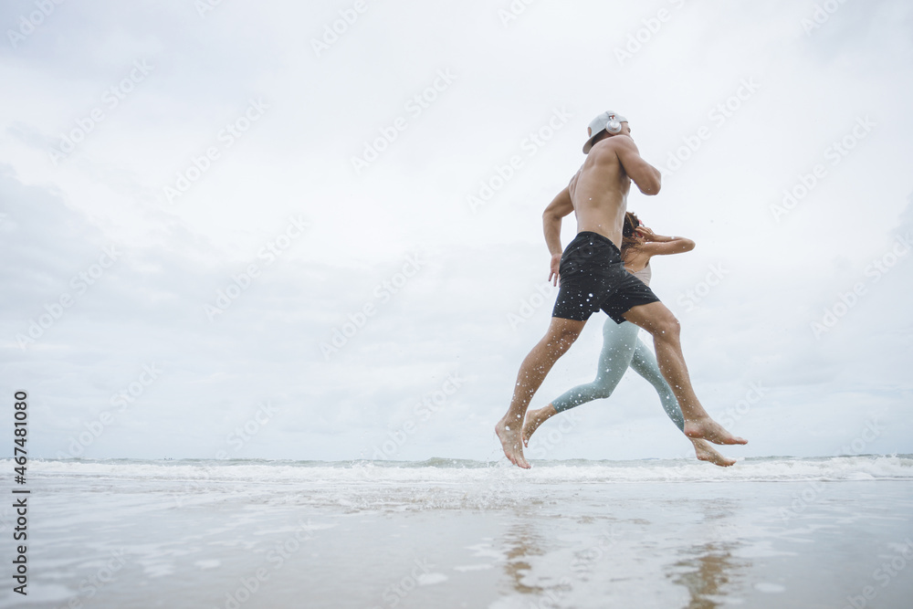 Runners. Young couple running on beach.  Sport runners jogging on beach working out smiling happy. Fitness exercise concept