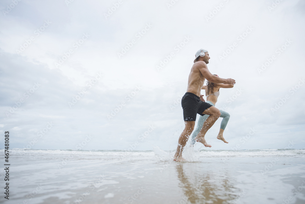Runners. Young couple running on beach.  Sport runners jogging on beach working out smiling happy. Fitness exercise concept