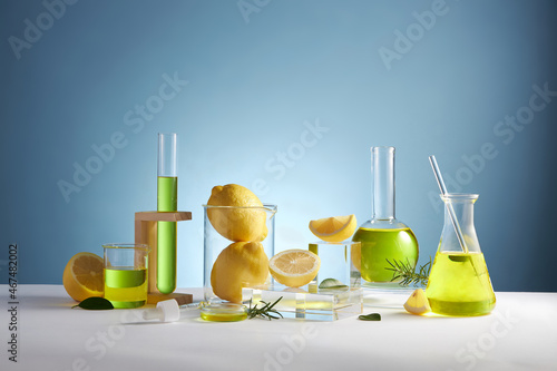 Lemon extract in test tube petri dish and lemon and sliced lemon , green leaf in a blue background blank space for product advertising , front view , photography experiment content 