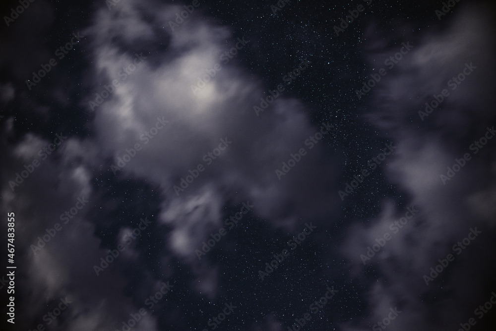 Stars in the night sky among clouds in the moonlight