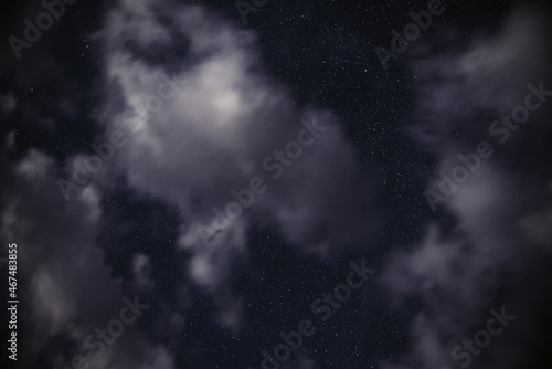 Stars in the night sky among clouds in the moonlight