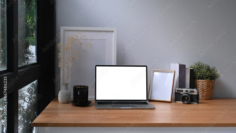 Fototapeta premium Stylish workplace with laptop computer, picture frame and houseplant.