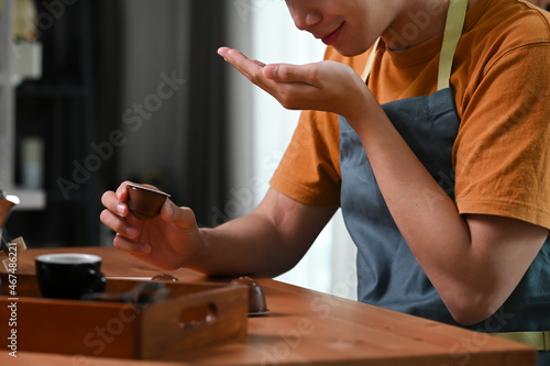 Young asian man smelling roasted coffee beans in his hands.