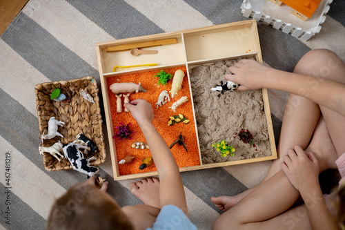 Touch drawer with rainbow rice inside. Children hand touch the texture. Montessori material concept for toddlers.
