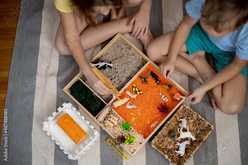 Touch drawer with rainbow rice inside. Children hand touch the texture. Montessori material concept for toddlers.