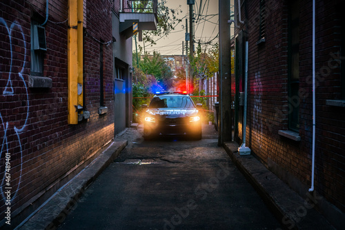 Fotografie Police car in a dark alley in Montreal, Canada with flashing red and blue lights