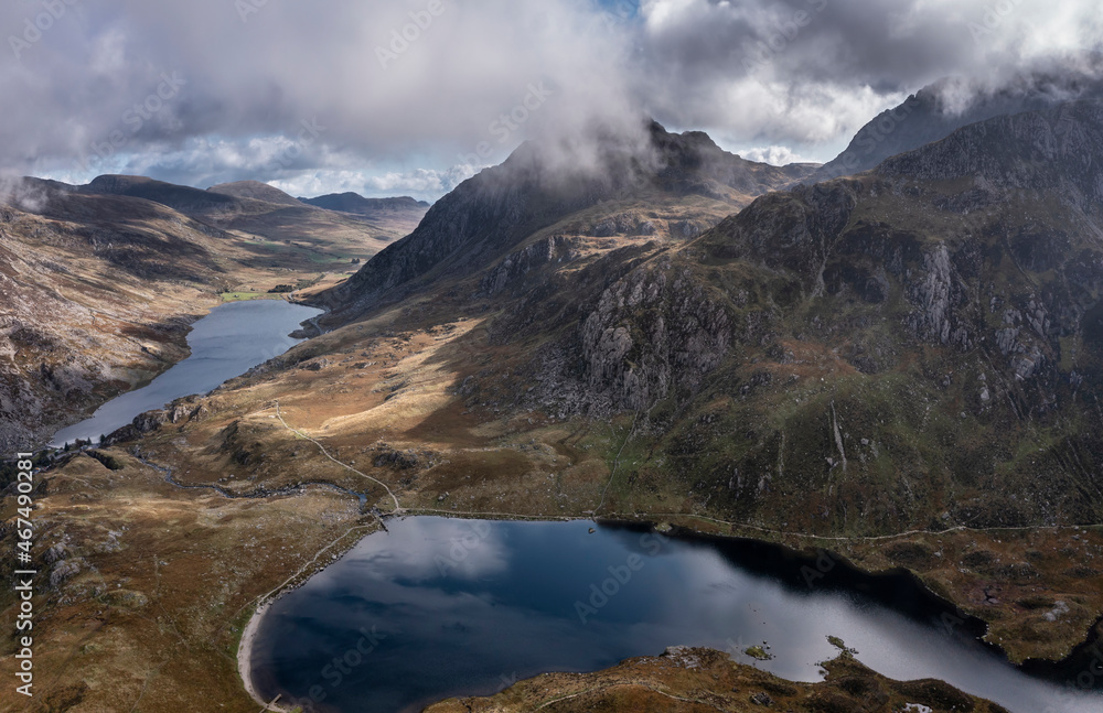 Aerial view of flying drone Epic Autumn Fall landscape image of view along Ogwen vslley in Snowdonia National Park with moody sky and mountains