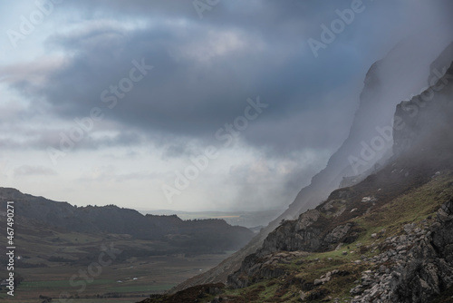 Epic mountain landscape image of Pen Yr Ole Wen in Snowdonia National Park with low cloud on peak and moodyfeel photo