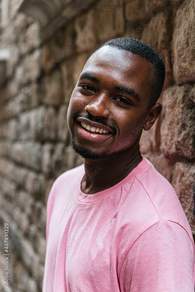 vertical portrait of an afro american young man. He is looking at camera with a stone wall on the background vertical portrait of an afro american young man. He is looking at camera with a stone wall on the background