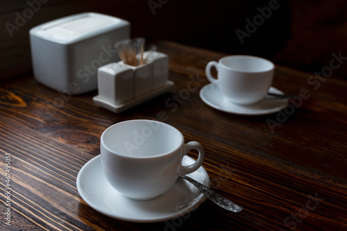 Empty white cups and saucers on a wooden table in a cafe. Cozy tea party.