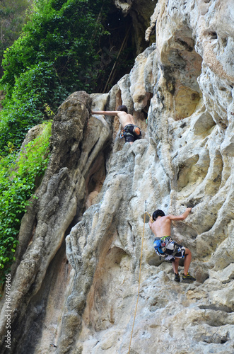 Thai people climber and foreign mountaineer travelers sport rock climbing at Dragon Crest Precipice Mountain and Railay Stone cliffs and travel visit rest relax in Ao Nang beach bay in Krabi, Thailand