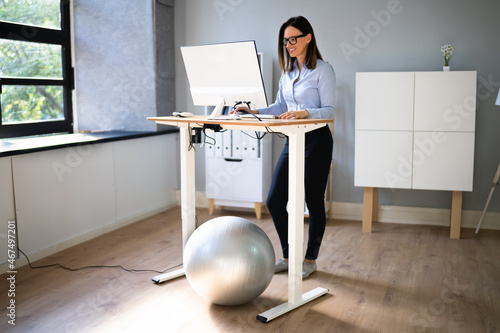 Foto Woman Using Adjustable Height Standing Desk In Office