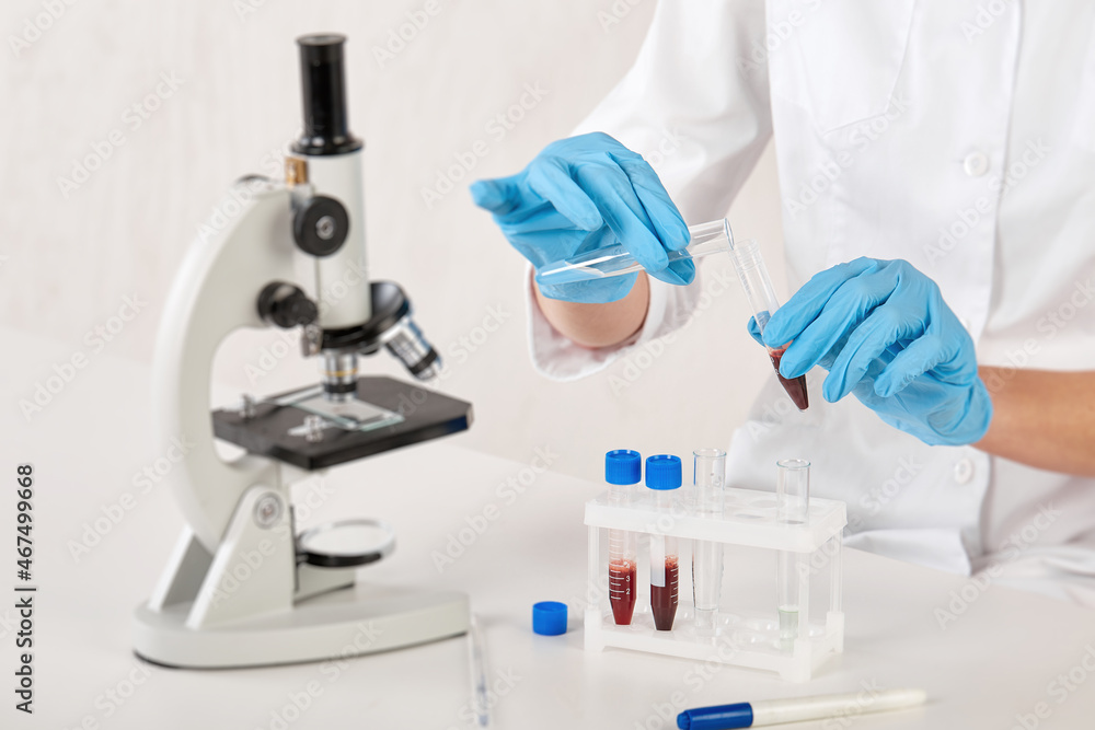 the hands of a laboratory assistant transfusing blood into a test tube with a solution the hands of a laboratory assistant transfusing blood into a test tube with a solution