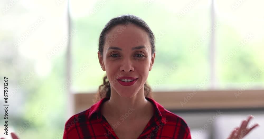 Positive ethnic woman waving hand and speaking with audience while recording video for blog in modern workspace Positive ethnic woman waving hand and speaking with audience while recording video for blog in modern workspace
