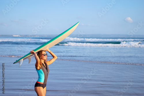 It's time for surfing! Hobby and vacation. Pretty young woman holding surf board on the sea shore.