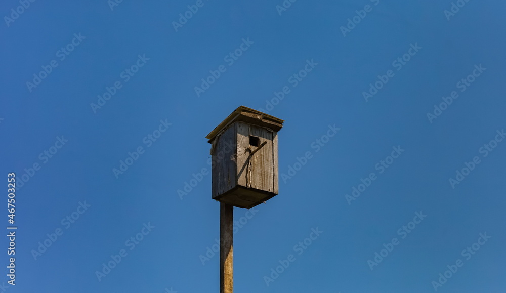 Old bird house (birdhouse) close-up against the blue sky in summer Old bird house (birdhouse) close-up against the blue sky in summer