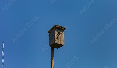 Old bird house (birdhouse) close-up against the blue sky in summer