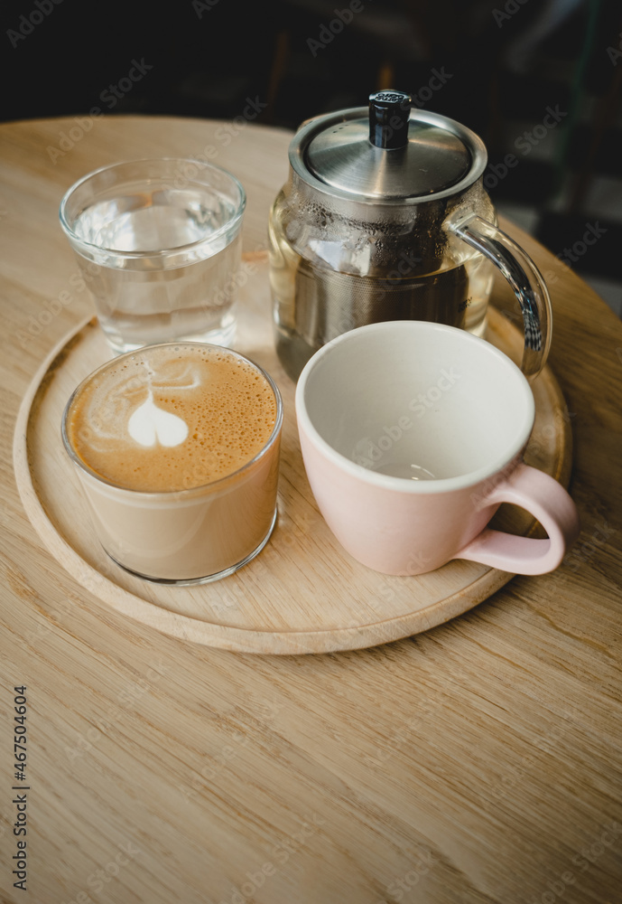 Wooden tray with drinks. Cappuccino, empty cup, glass teapot, water. Cozy coffee shop. Copy space. Wooden tray with drinks. Cappuccino, empty cup, glass teapot, water. Cozy coffee shop. Copy space.
